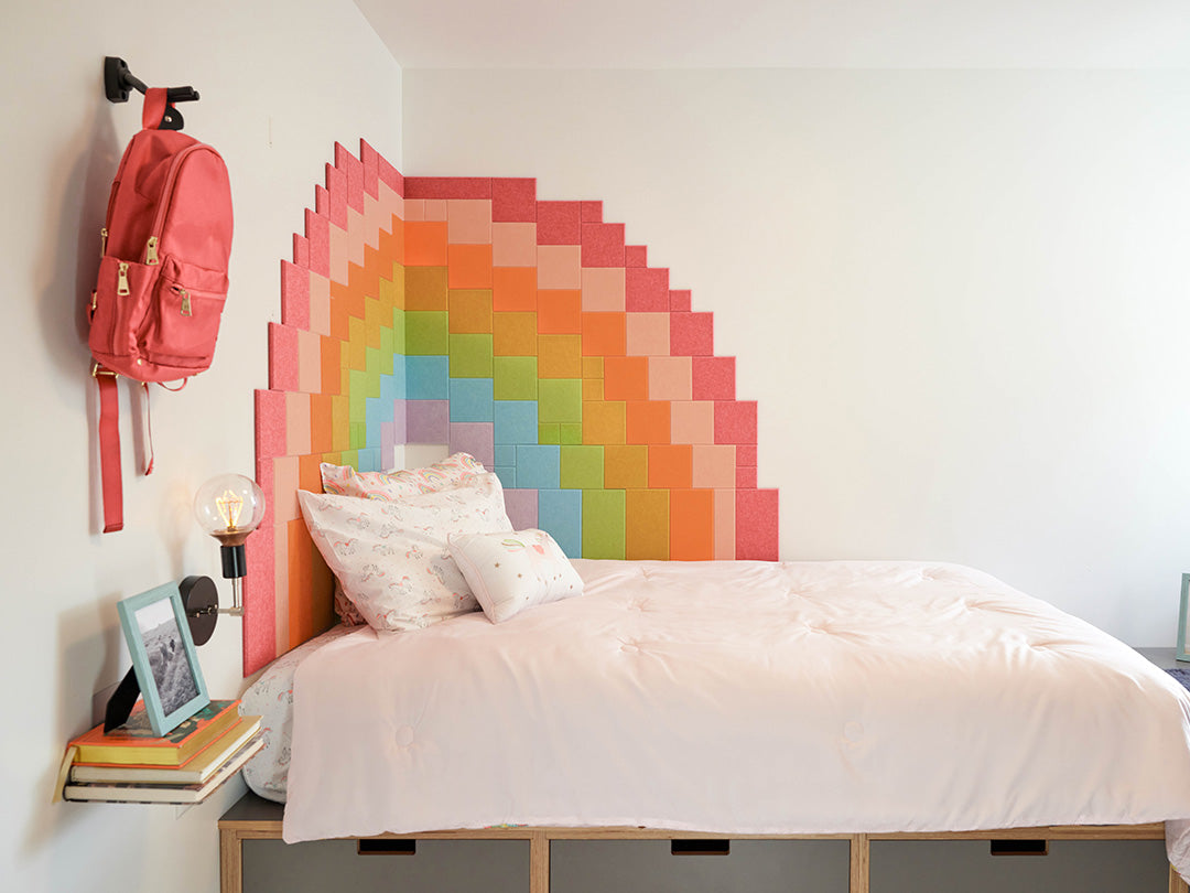 Bedroom with a colorful rainbow headboard and pink backpack.