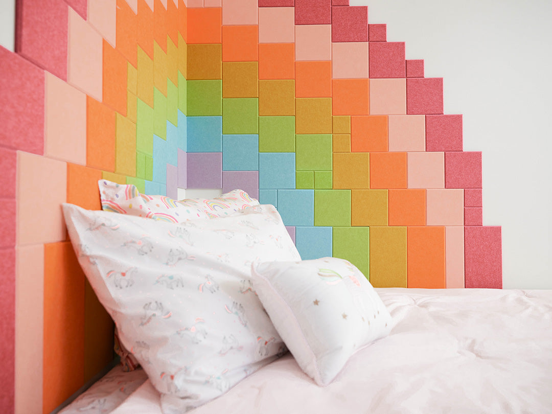 Colorful geometric wall paneling behind a bed with pillows