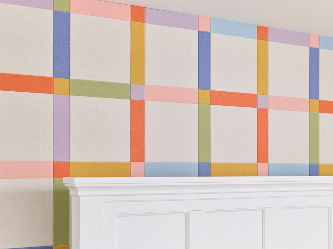 Felt Right wall art design in a bedroom with a plaid design using pink, orange, green, and blue felt tiles behind a headboard of a bed.