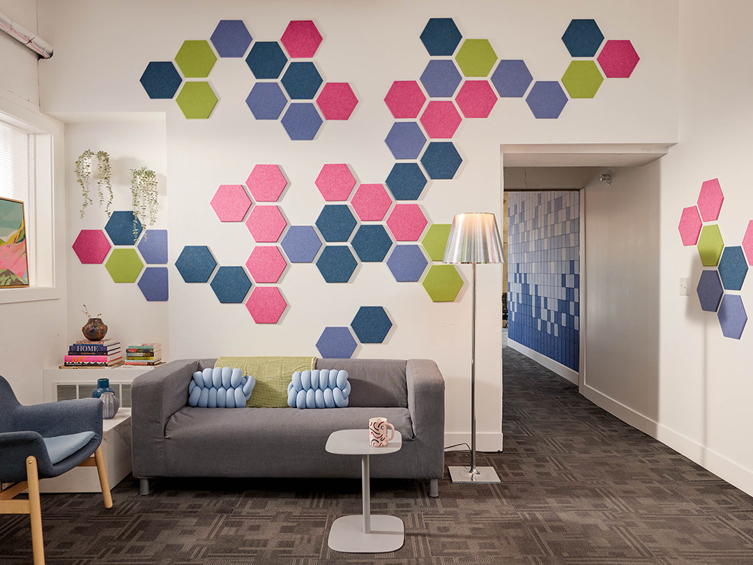 Modern living room with colorful hexagonal wall art and a gray sofa.