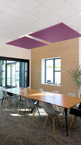 Two purple square acoustic panels suspended from ceiling above conference table in modern office space.