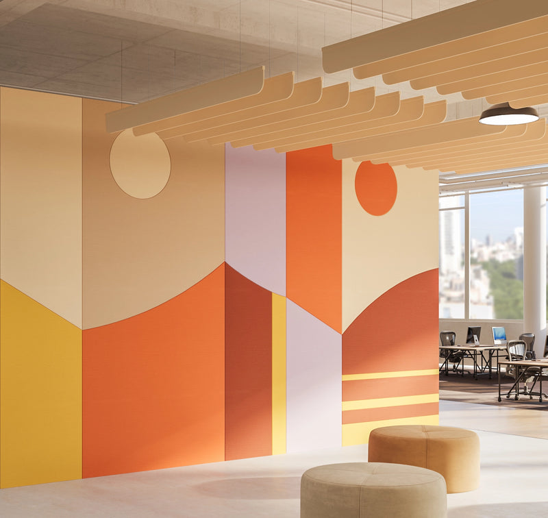 A modern interior space with a large abstract geometric wall mural in warm tones of orange, beige, yellow, and white. The room features layered wooden ceiling panels, pendant lights, and round upholstered ottomans in the foreground, with office desks visible through a large window on the right.
