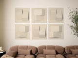 Set of six beige dimensional wall tiles with geometric raised and recessed patterns displayed above a brown sofa.