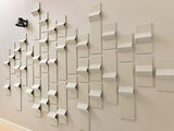 Beige 3D wall tiles with angled geometric surfaces mounted on a beige wall, creating a dimensional pattern effect.