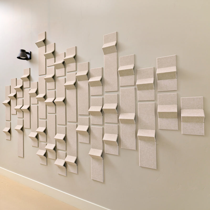 Light tan acoustic tiles made of felt on a wall with points of dimension