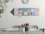 Children's art display on a wall with a table in front featuring art supplies.