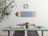 Colorful wall art shaped like a pencil above a table with stationery items.