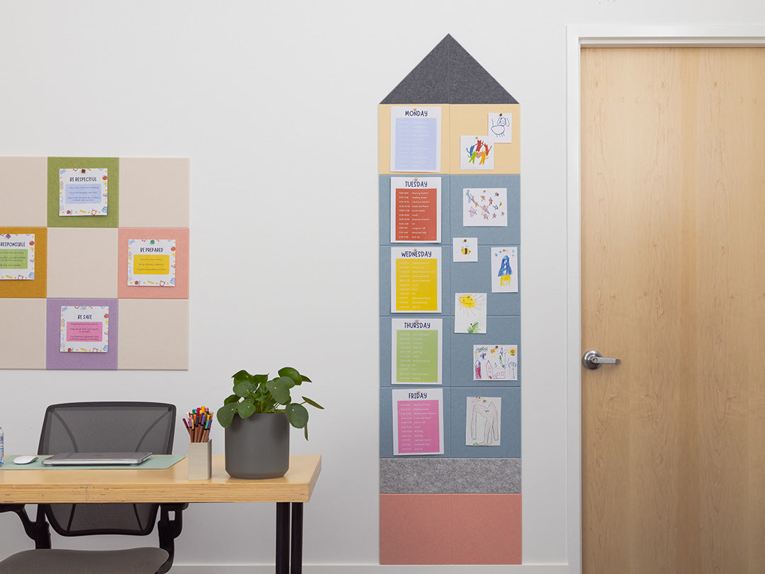 Framed colorful bulletin board with notes on a white wall next to a desk.
