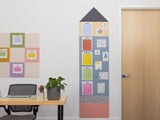 Framed colorful bulletin board with notes on a white wall next to a desk.