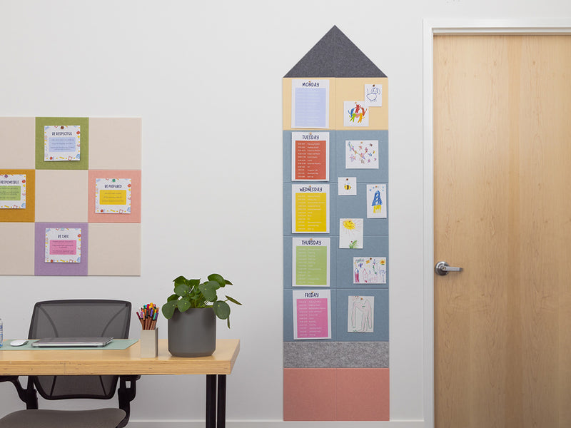 Framed colorful bulletin board with notes on a white wall next to a desk.
