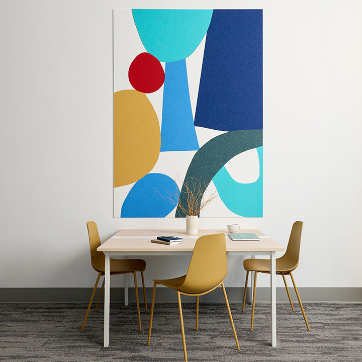 Large acoustic felt mural on white wall above table and yellow chairs