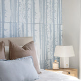 A close-up of a wallpaper or fabric pattern featuring vertical light blue tree trunks on a white background.
