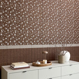 Brown ceramic tile with white flowering branches and blossoms in repeating pattern.