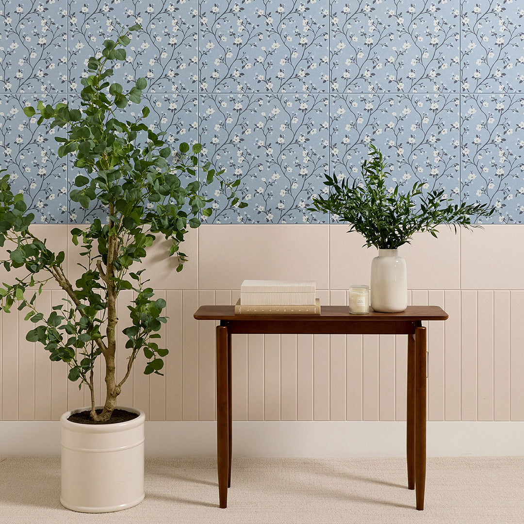 Blue-gray tile with delicate white floral and vine pattern displayed on wall above cream subway tiles.