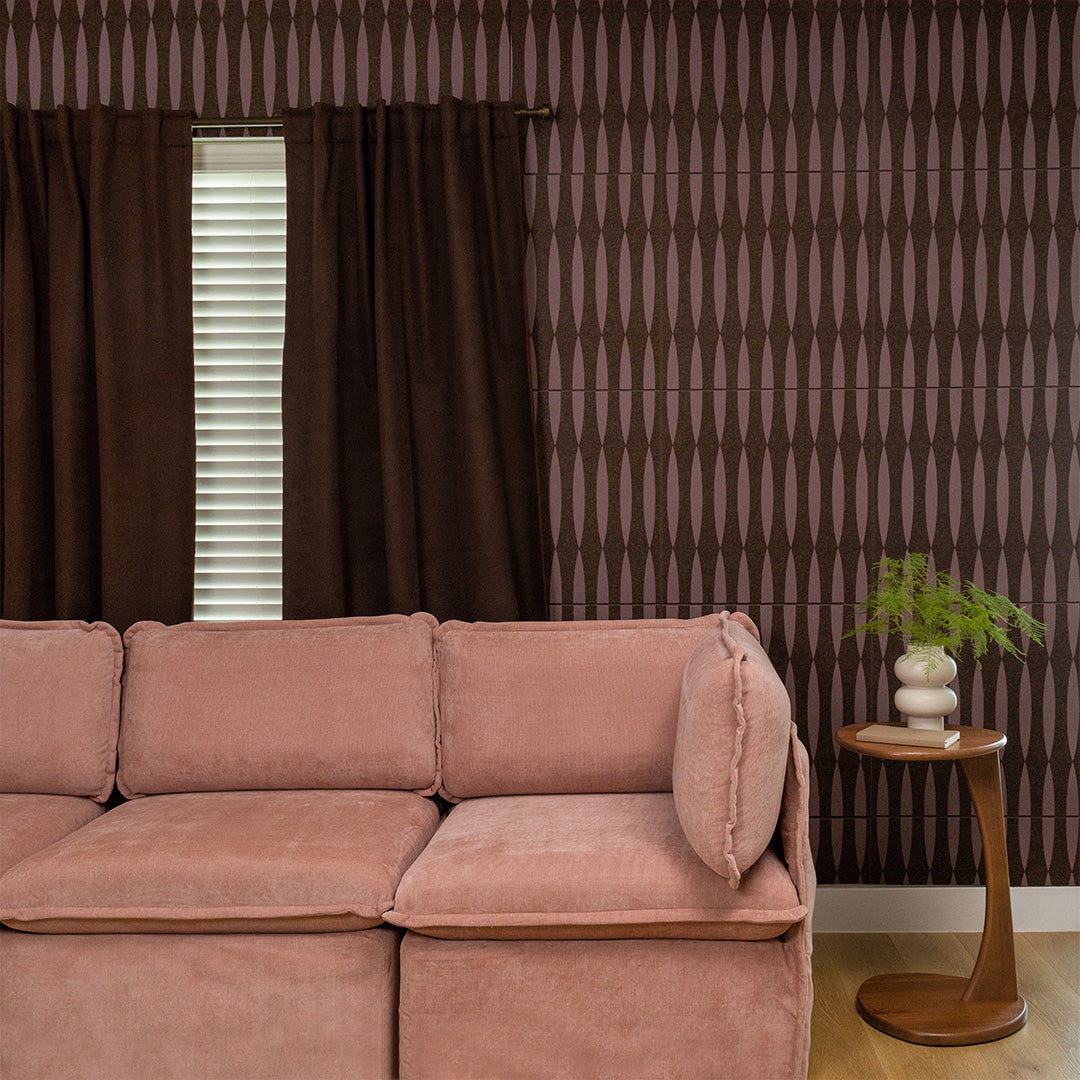 Brown tile with vertical striped and geometric diamond pattern design on wall behind pink sofa.