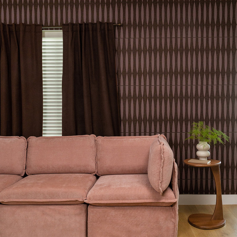 Brown tile with vertical striped and geometric diamond pattern design on wall behind pink sofa.