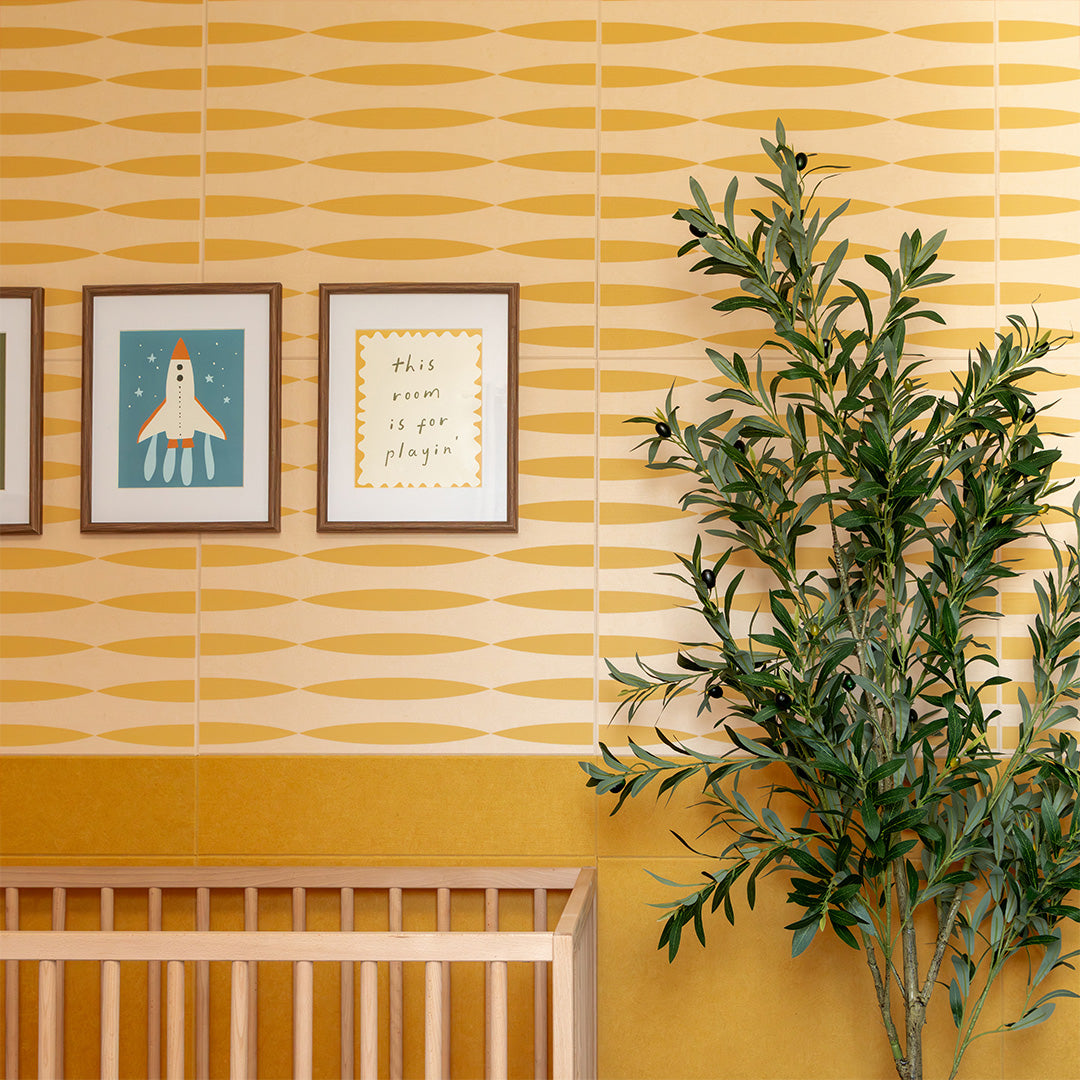 Tan and gold geometric patterned tile with repeating oval shapes displayed on nursery wall.