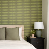 Green and tan striped wall tiles installed in a bedroom above a bed headboard.