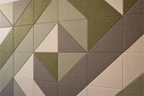Geometric wall tiles in green, tan, and gray with triangular faceted surfaces creating a 3D prism pattern.
