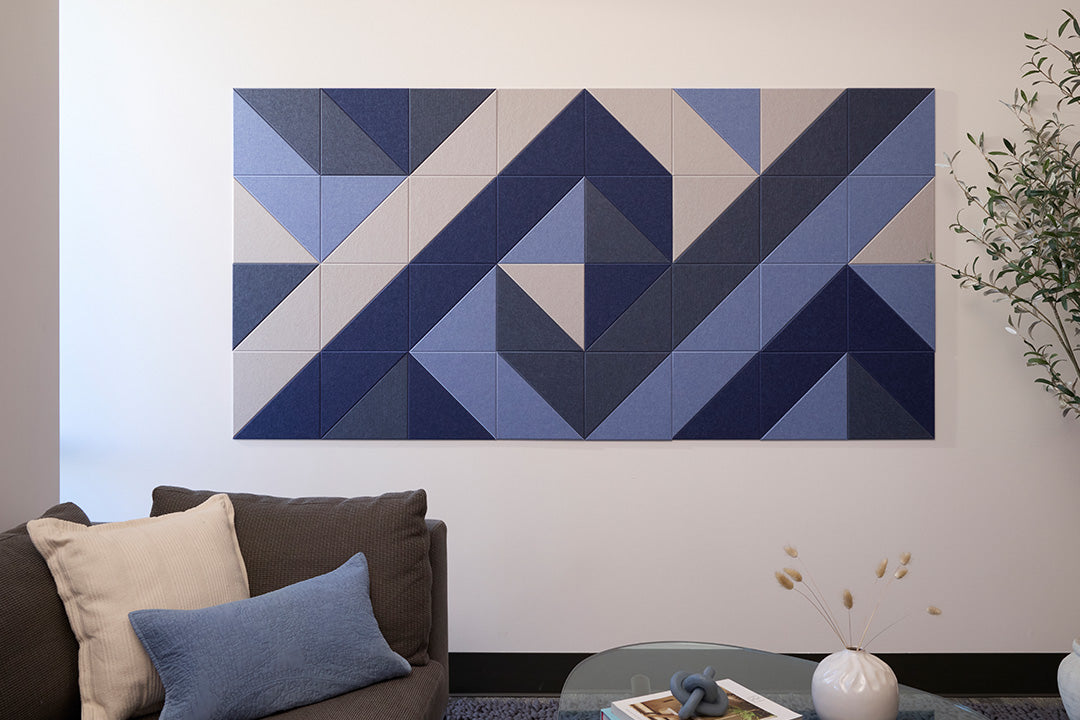 A Felt Right wall design, geometric artwork featuring various shades of blue tiles arranged in a pattern on a wall above a sofa.