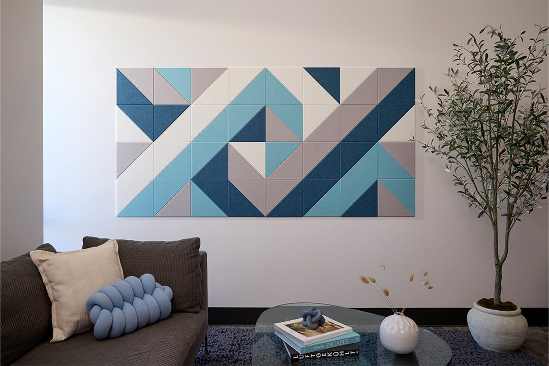 A geometric Felt Right artwork hanging on a wall over a sofa, consisting of multiple triangles in shades of blue and beige.