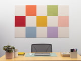 Colorful square acoustic panels on a wall above a desk with office supplies.