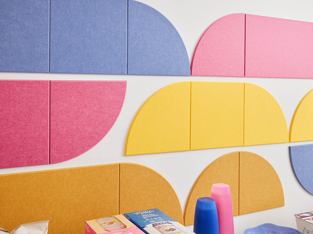 Break room with a white table and yellow chairs against a colorful geometric wall.