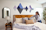 Geometric diamond wall decals in shades of blue, purple, and gray arranged above a wooden bed with pillows.