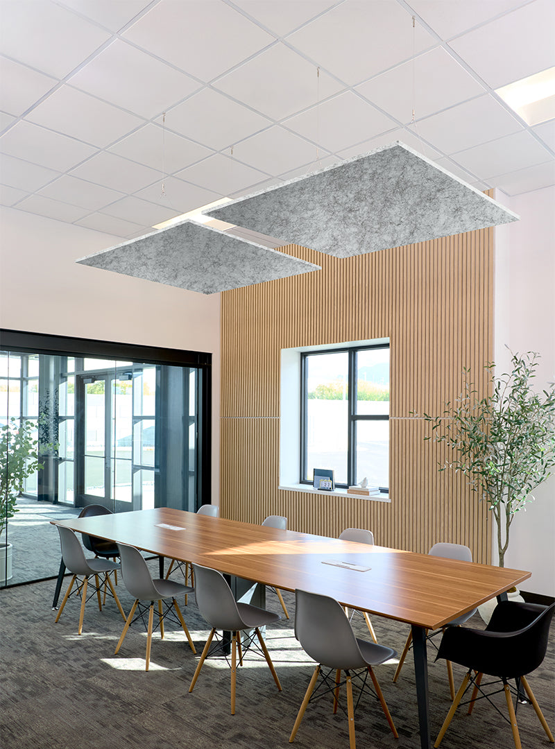 Modern conference room with a long wooden table, gray and black chairs, a slatted wood accent wall, large windows, and two rectangular gray acoustic ceiling panels.