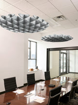 Modern conference room with a long wooden table, black office chairs, large ceiling-mounted sculptural pendant lights, white walls, and glass partition walls.