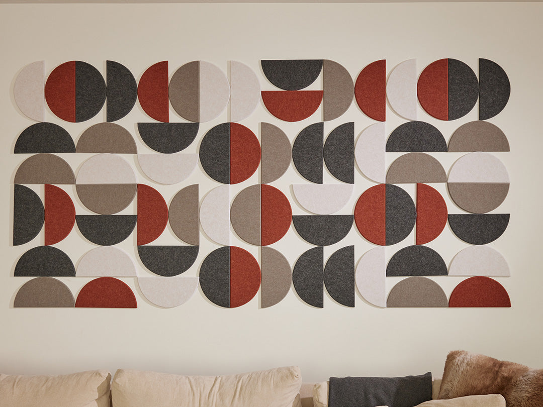 Geometric wall art with circular patterns in red, black, and gray on a beige wall.