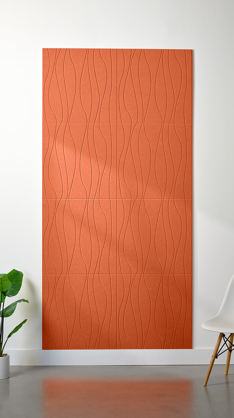 Orange Felt Right 4’ x 8’ PET felt panel with flowing lines engraved into the material against a white wall. A plant and chair are in the foreground.