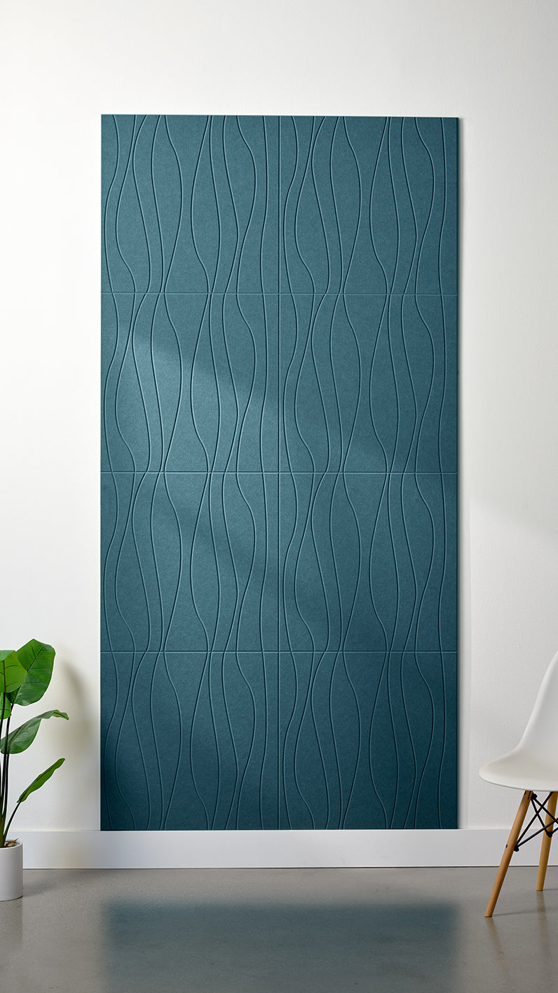 Blue Felt Right 4’ x 8’ PET felt panel with flowing lines engraved into the material against a white wall. A plant and chair are in the foreground.