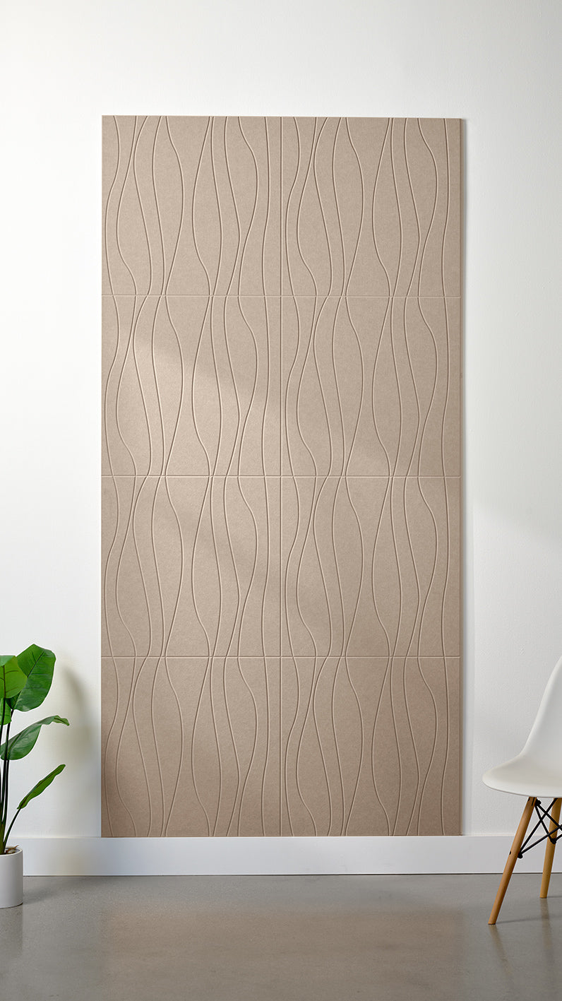 Camel Felt Right 4’ x 8’ PET felt panel with flowing lines engraved into the material against a white wall. A plant and chair are in the foreground.