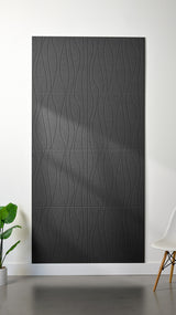Dark grey Felt Right 4’ x 8’ PET felt panel with flowing lines engraved into the material against a white wall. A plant and chair are in the foreground.