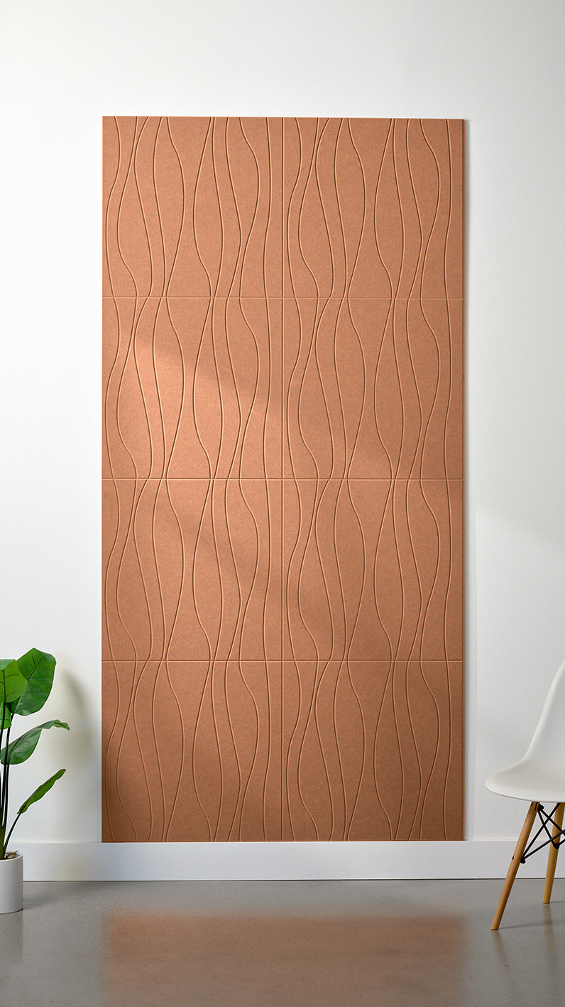 Light orange Felt Right 4’ x 8’ PET felt panel with flowing lines engraved into the material against a white wall. A plant and chair are in the foreground.