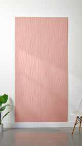 Light pink Felt Right 4’ x 8’ PET felt panel with flowing lines engraved into the material against a white wall. A plant and chair are in the foreground.
