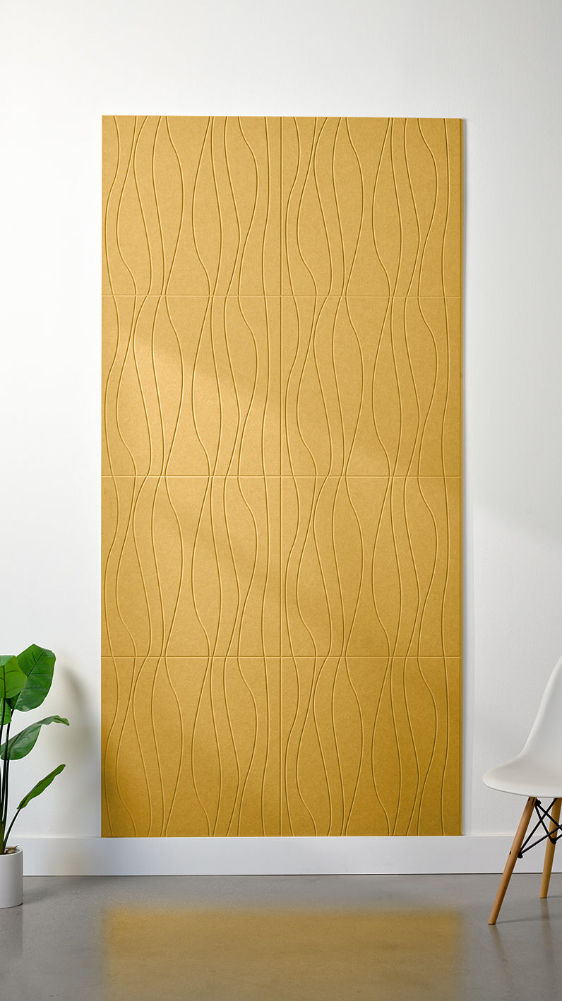 Yellow Felt Right 4’ x 8’ PET felt panel with flowing lines engraved into the material against a white wall. A plant and chair are in the foreground.