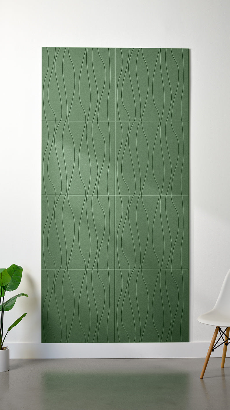 Green Felt Right 4’ x 8’ PET felt panel with flowing lines engraved into the material against a white wall. A plant and chair are in the foreground.