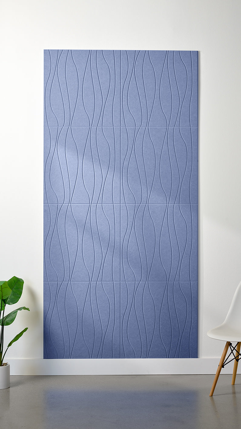 Periwinkle Felt Right 4’ x 8’ PET felt panel with flowing lines engraved into the material against a white wall. A plant and chair are in the foreground.
