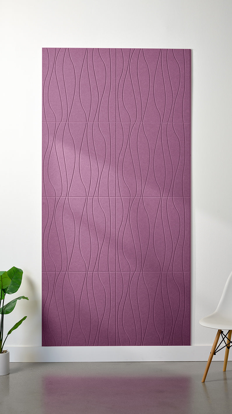 Deep purple Felt Right 4’ x 8’ PET felt panel with flowing lines engraved into the material against a white wall. A plant and chair are in the foreground.