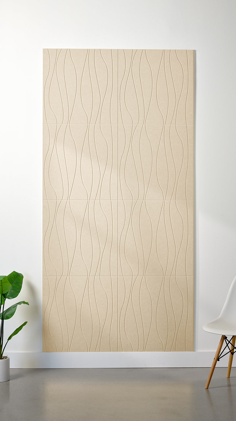 Beige Felt Right 4’ x 8’ PET felt panel with flowing lines engraved into the material against a white wall. A plant and chair are in the foreground.