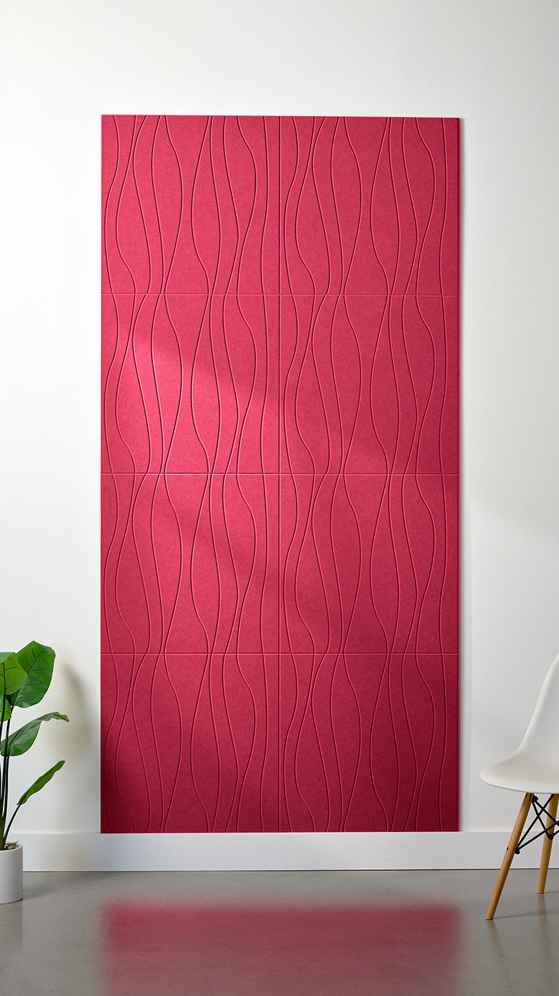 Bright red Felt Right 4’ x 8’ PET felt panel with flowing lines engraved into the material against a white wall. A plant and chair are in the foreground.