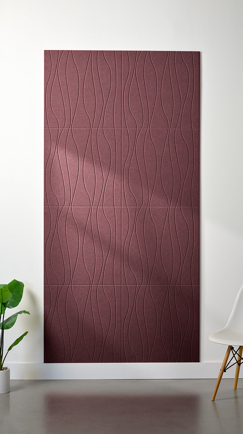Maroon Felt Right 4’ x 8’ PET felt panel with flowing lines engraved into the material against a white wall. A plant and chair are in the foreground.