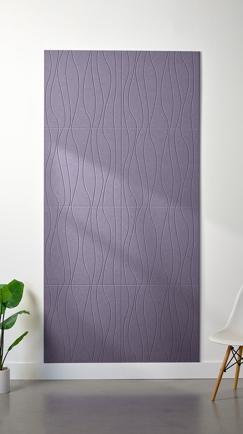 Light purple Felt Right 4’ x 8’ PET felt panel with flowing lines engraved into the material against a white wall. A plant and chair are in the foreground.