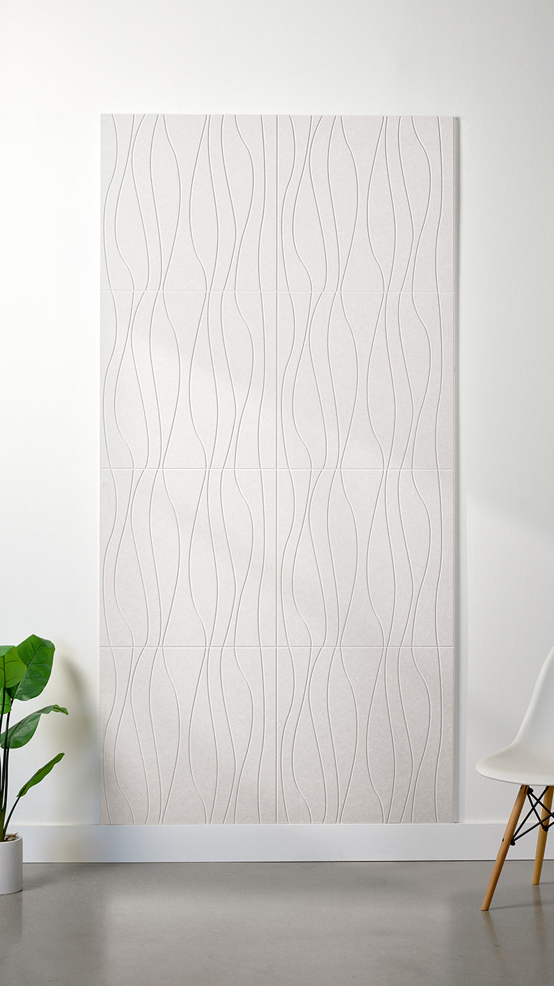 White Felt Right 4’ x 8’ PET felt panel with flowing lines engraved into the material against a white wall. A plant and chair are in the foreground.