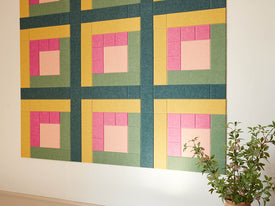 Colorful geometric wall art with pink, yellow, and green squares on a white wall.