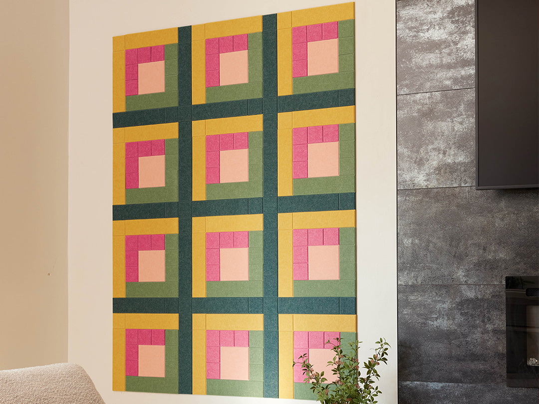 Colorful quilt with geometric pattern on a wall next to a fireplace.