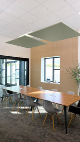 Two sage green square acoustic baffles suspended from ceiling above conference table in modern office space.