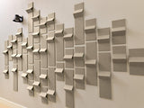 Beige 3D wall tiles arranged in staggered pattern with folded edges creating geometric shadows on white wall.